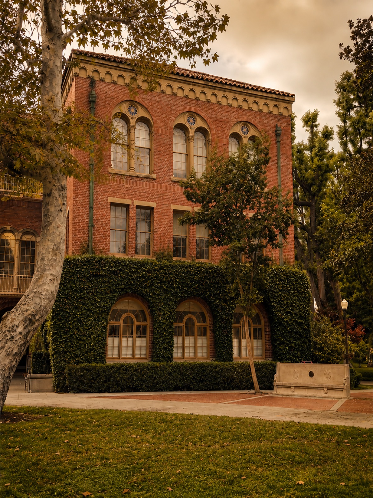 An ivy-covered brick hall and stone bench on the University of Southern California campus